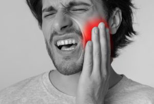 man holding cheek in pain from severe toothache